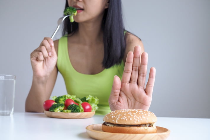 woman-eat-salad-no-hamburger-hand-unhealthy-food