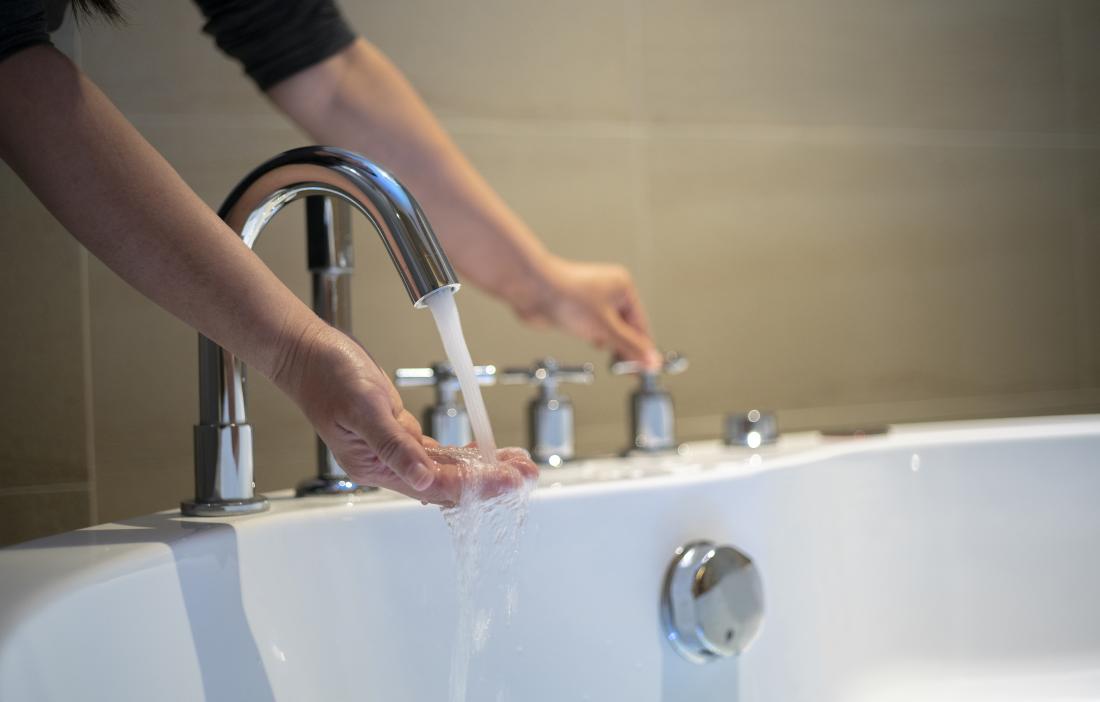 person-holding-their-hand-under-running-water-from-a-tap-into-a-bath