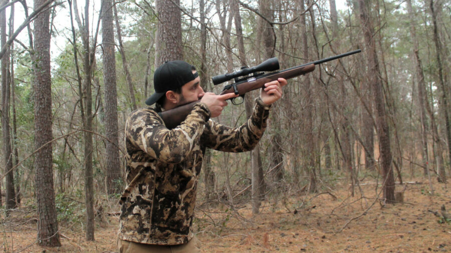 a man hunting in the woods with centerfire rifle