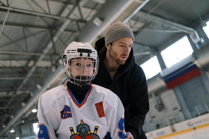 dad learning his kid to play hockey