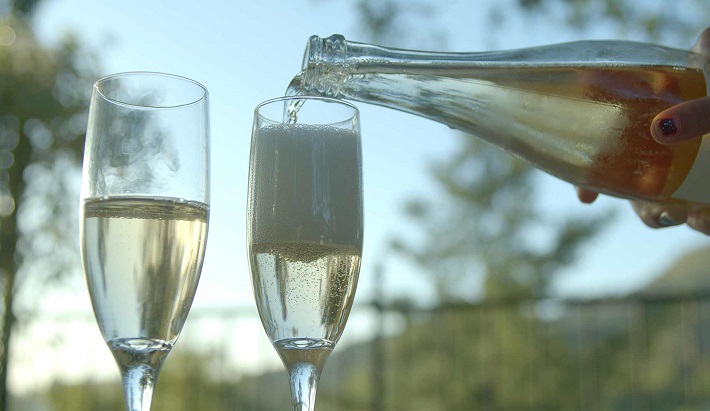 woman pouring Australian sparkling wine in two glasses