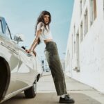 woman leaning on a car wearing green bottoms for women and white top